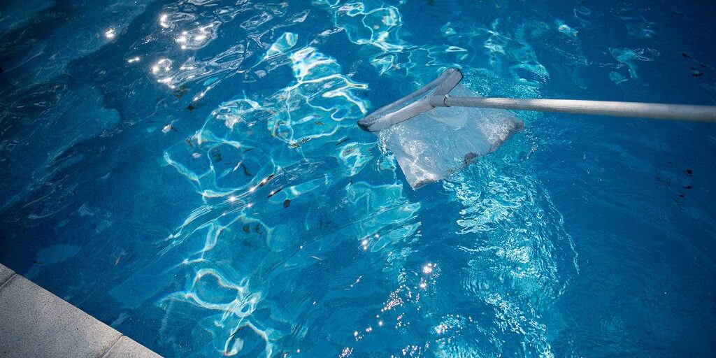 using a net to remove debris from a pool