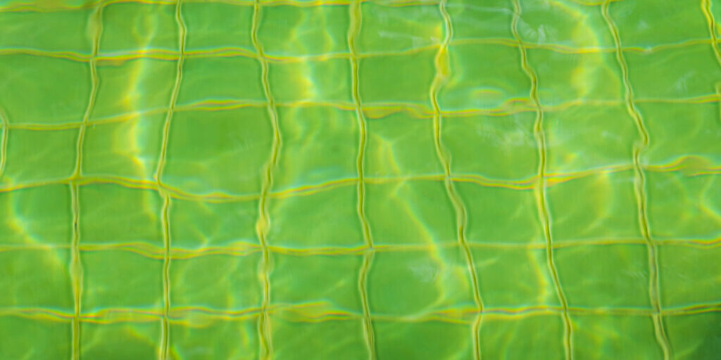 looking through green pool water at tiles