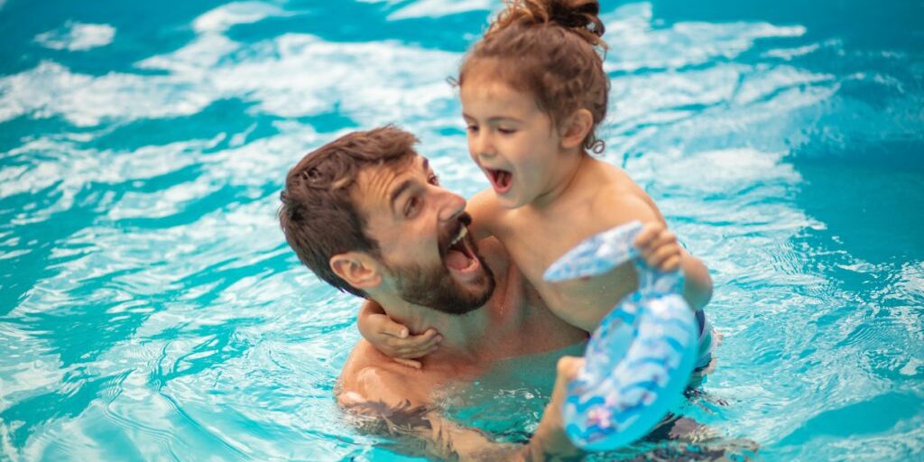 Father and son playing together in the swimming pool. Father and son playing together in the swimming pool.